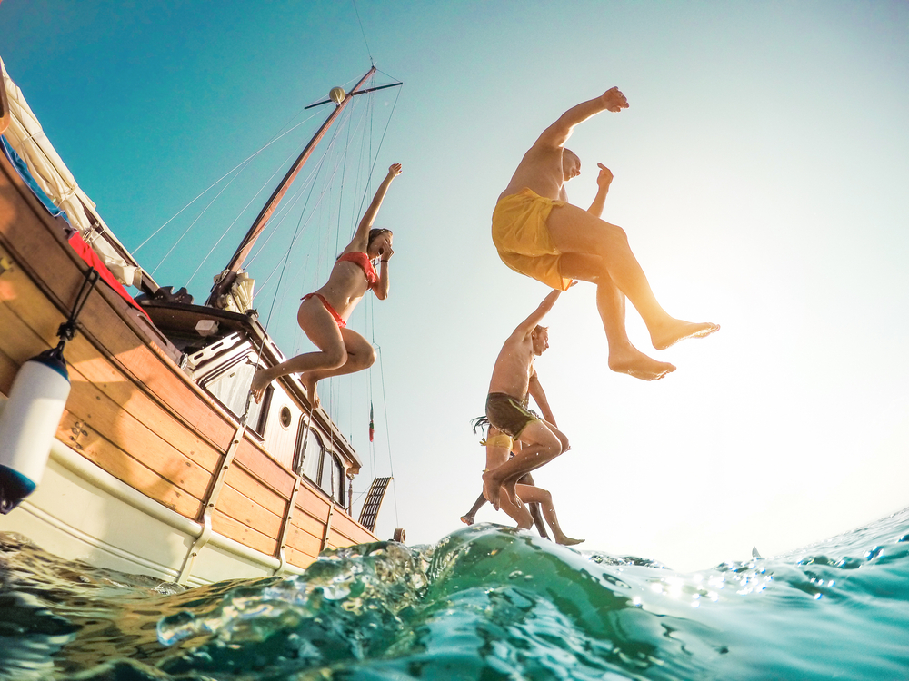 Happy,Friends,Diving,From,Sailing,Boat,Into,The,Sea,-